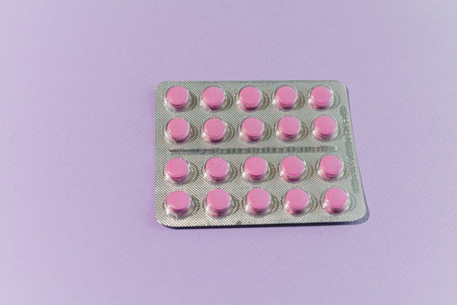A neatly arranged blister pack containing pink tablets on a solid purple surface.